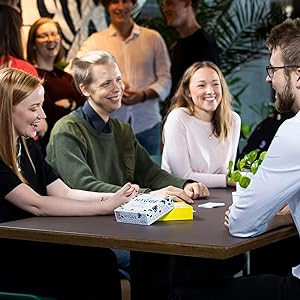 Collage students laughing playing tabletop conversation starter, card game, the hygge game, cozy